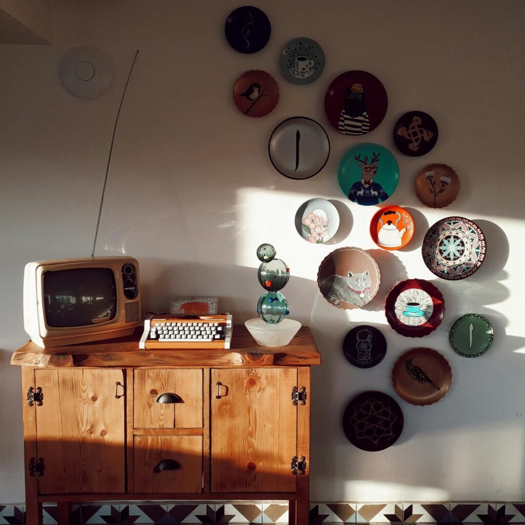 Retro living room setup featuring a vintage TV, typewriter, and decorative wall plates, bathed in warm daylight.